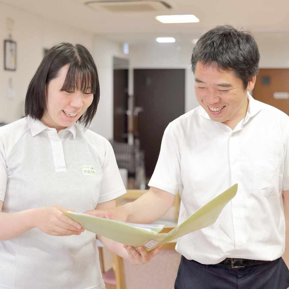 介護職員と男性スタッフが書類を確認する施設内での風景