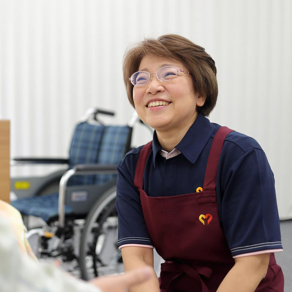 介護職員が笑顔で利用者と接している様子。施設内での日常的なケアシーン。